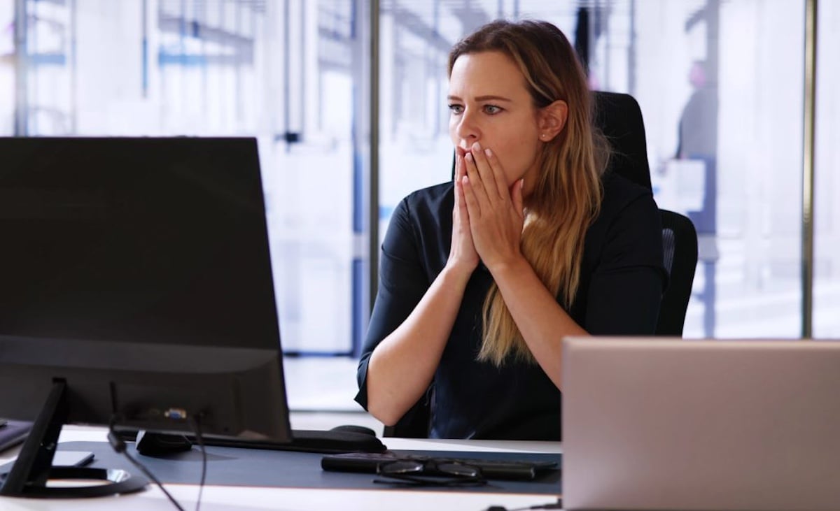 Kvinner gisper forskrekket og holder hendene over munnen av noe hun ser på en dataskjerm.